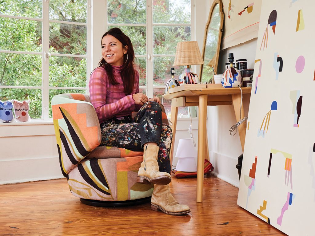 Artist JULU in paint-covered pants sitting in her studio