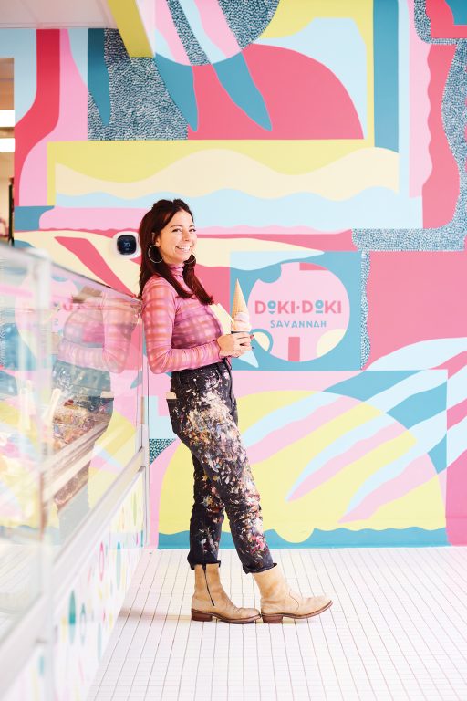 JULU holding an ice cream cone at Doki Doki, in front of the mural she painted.