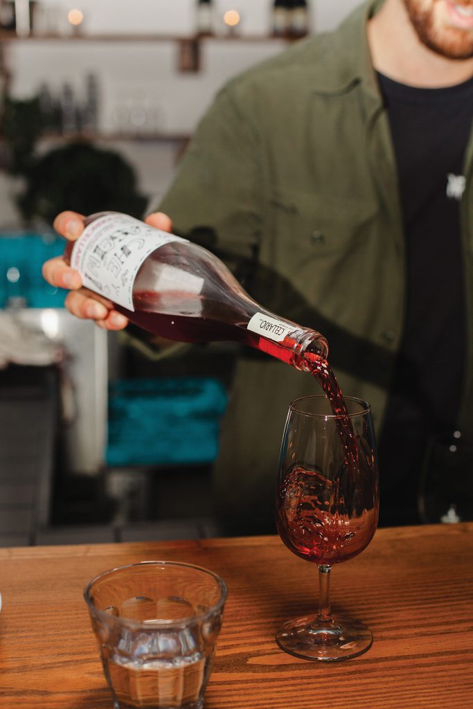 man pouring red wine into a wine glass