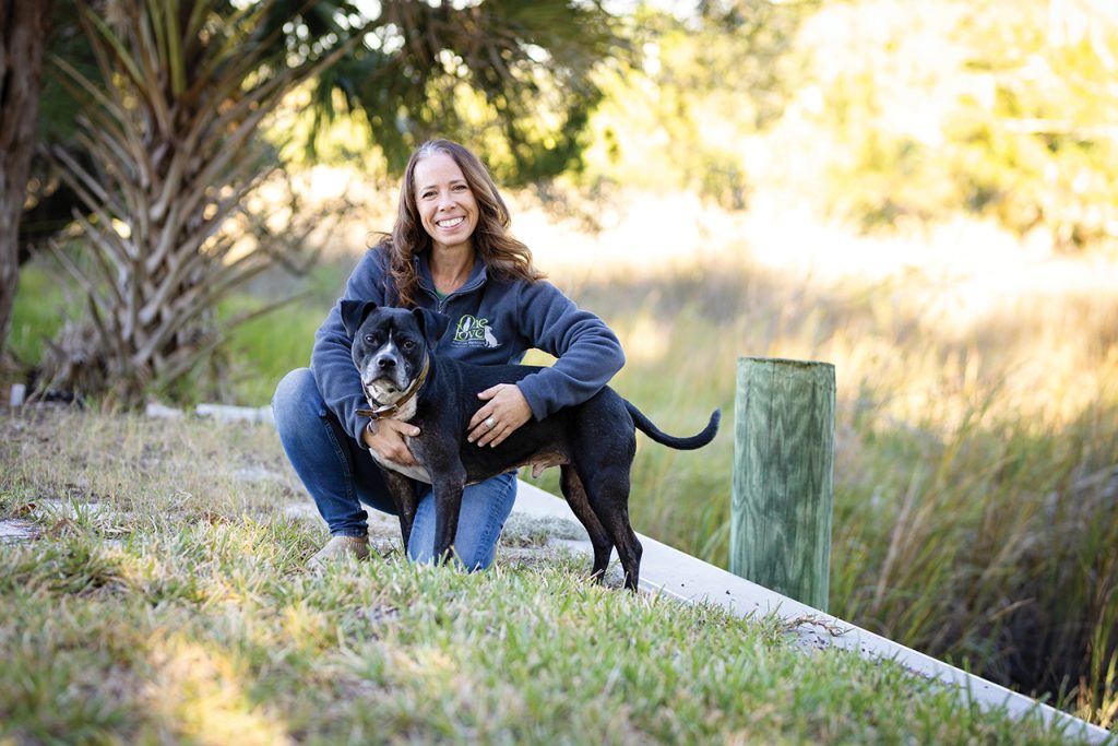 Woman kneeling in the grass and hugging a black dog