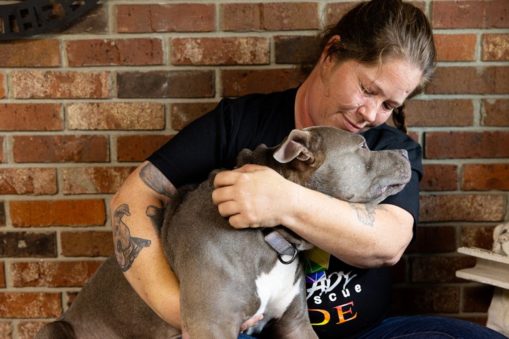 Woman hugging a tan pit bull