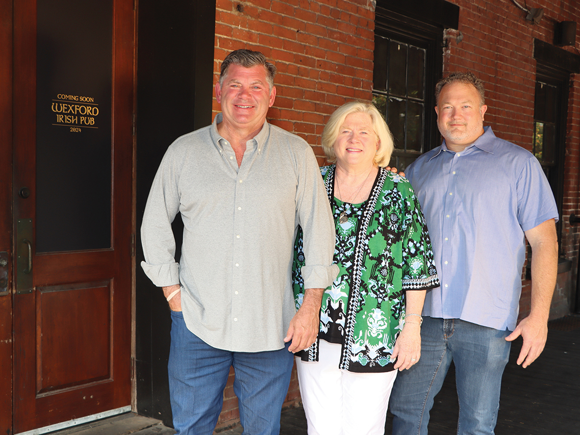 two men and a woman standing in front of a pub