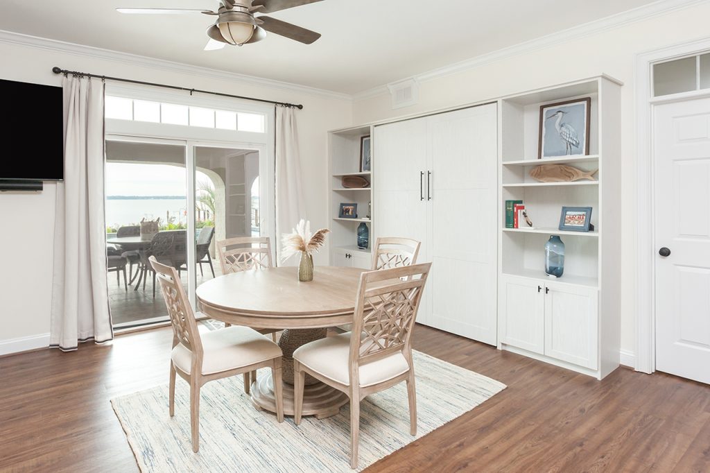 Small dining table in front of built in shelves and closed Murphy bed