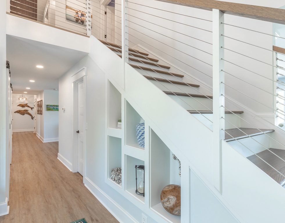 a stairwell with a wire bannister and built-in storage shelves below