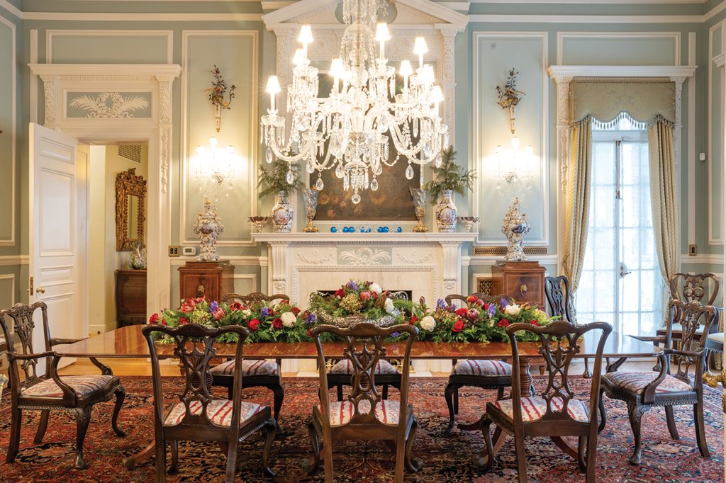 A crystal chandelier hangs over a dining room table decorated for the holidays