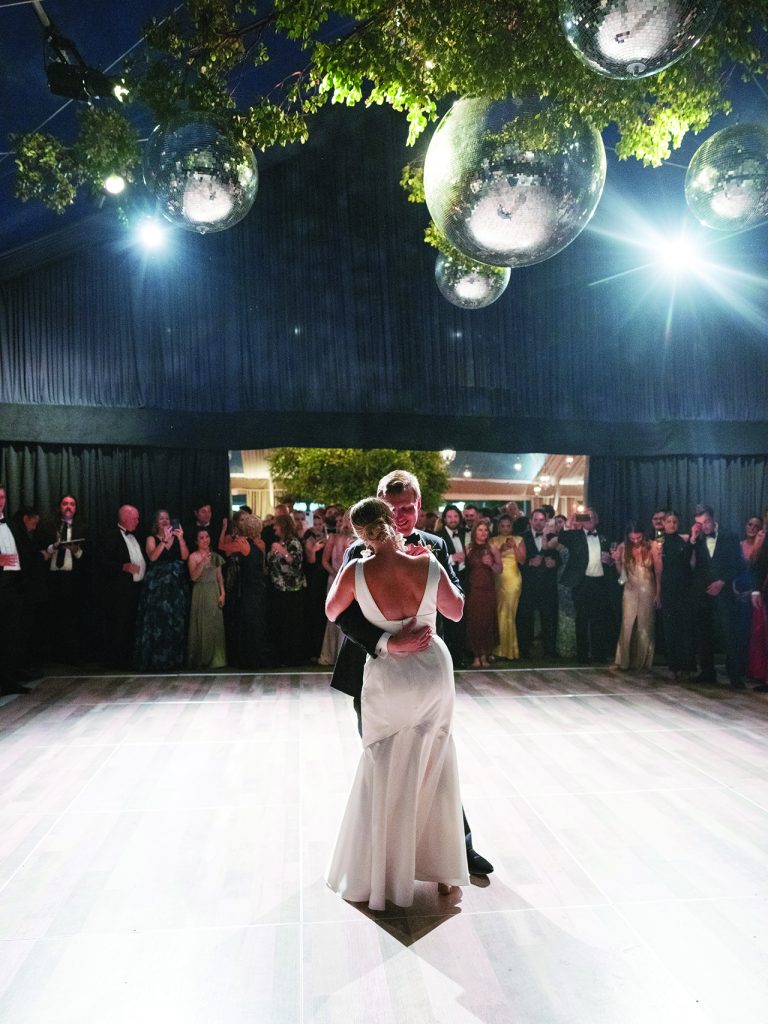 bride and groom dance closely with disco balls overhead