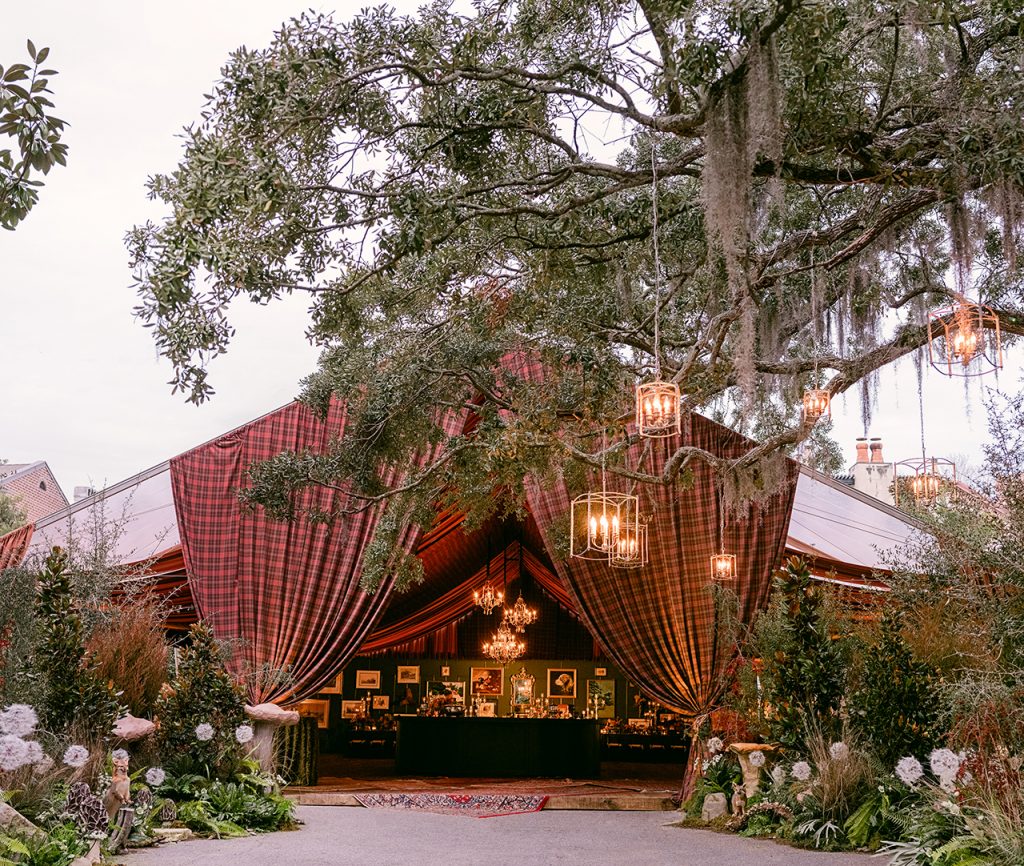 tent draped in a red tartan and surrounded by paper mâché mushrooms and taxidermy animals