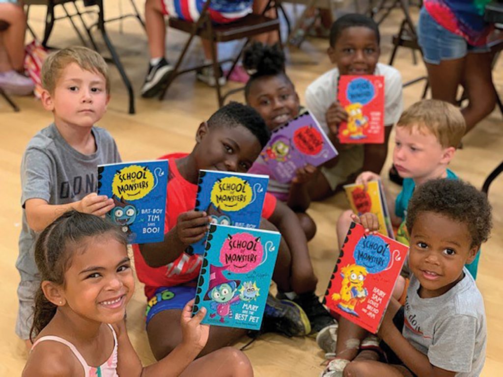 Children sitting on floor and holding up books