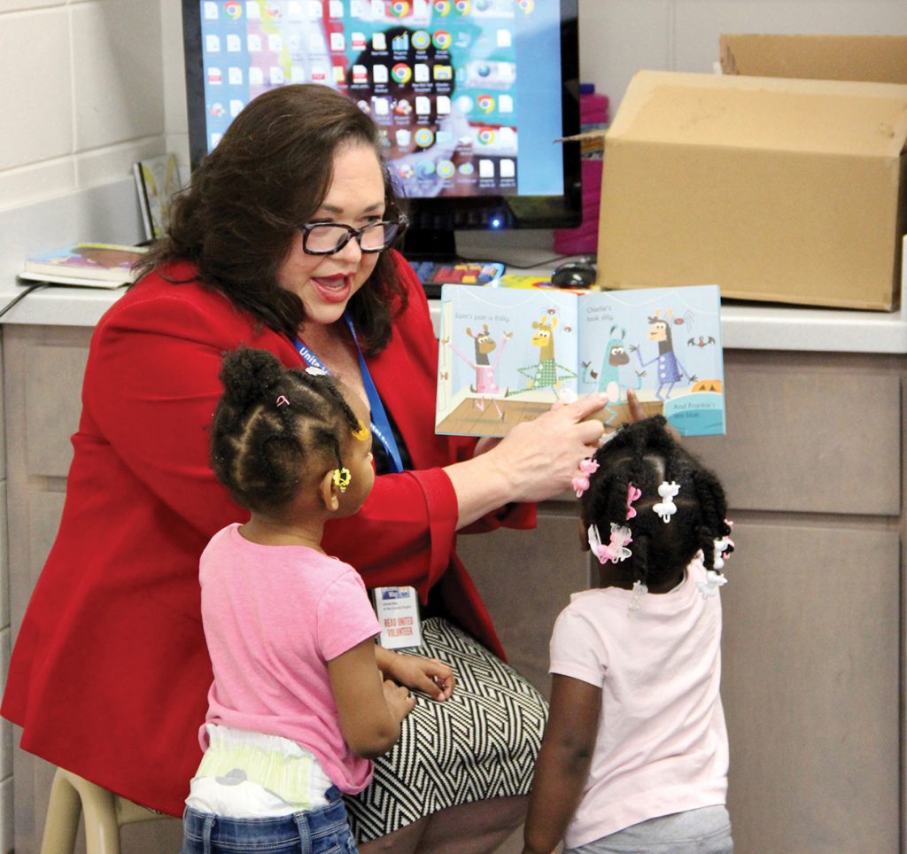 Woman reading a book to two little girls